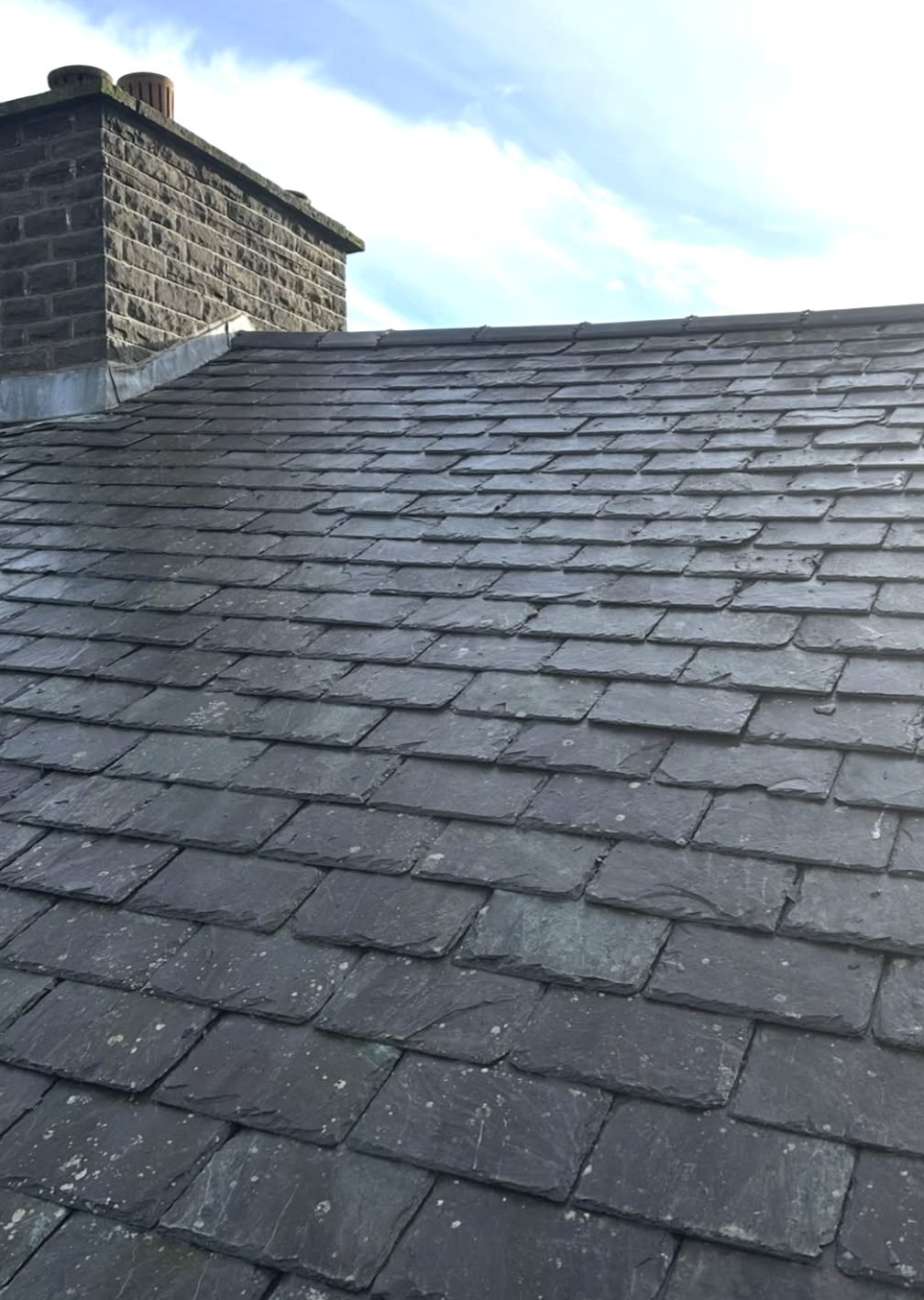 Natural slate roof with a stone chimney stack and lead flashing